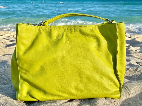 Tahitian lime bag front view on a sandy beach with ocean in the background