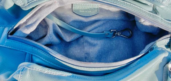 Close-up of the light grey bag on the inside with a visible brand tag and key leash.