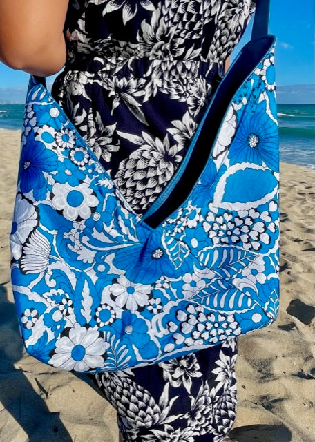 A woman wearing a floral dress holding the cobalt blue leather hobo bag reversed to show the vintage silky fabric lining.
