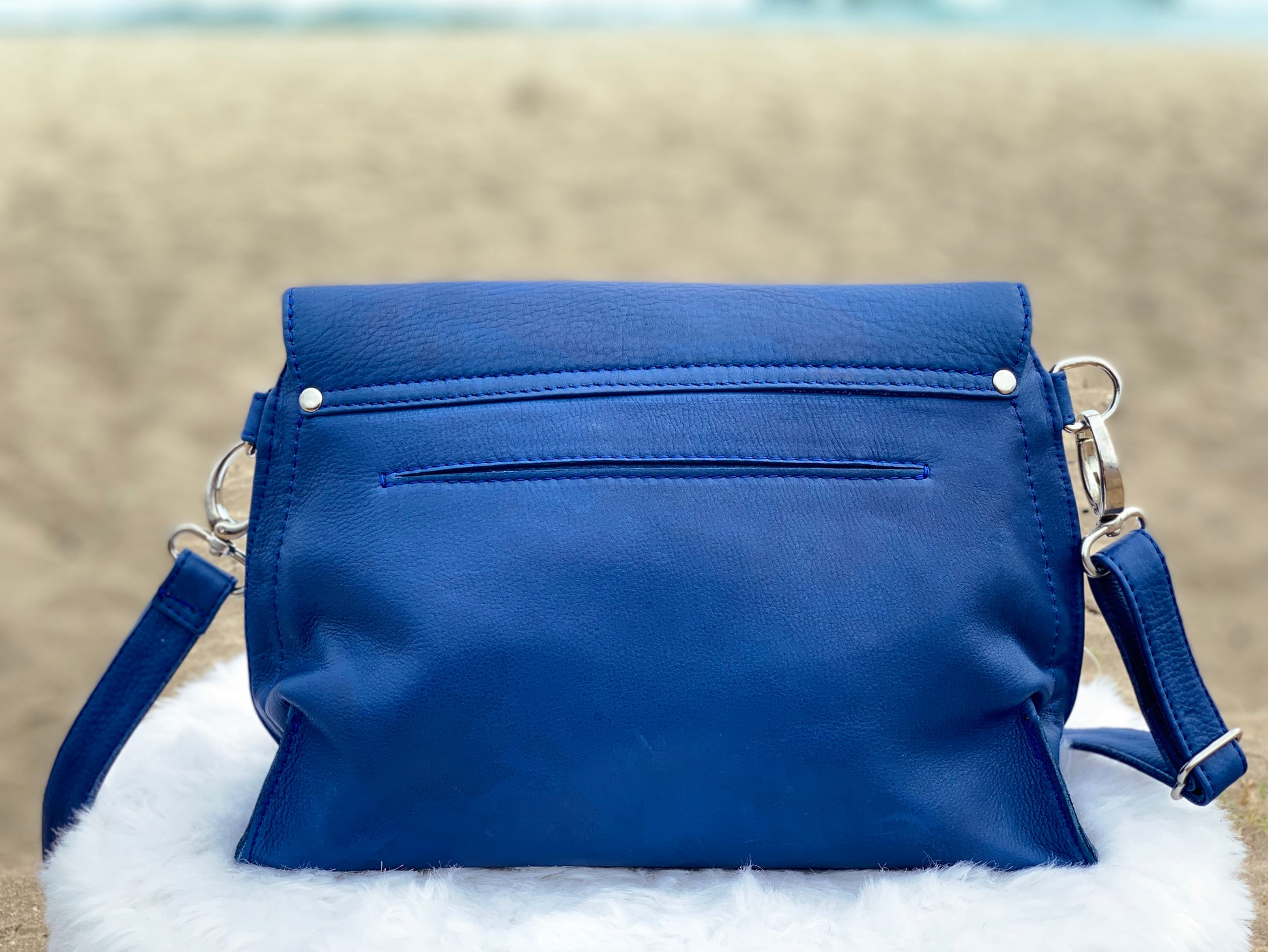 Blue Marine bag back view on a white surface with a blurred natural background