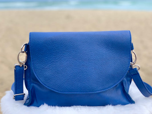 Blue Marine leather bag front view on a fluffy white surface with a beach background