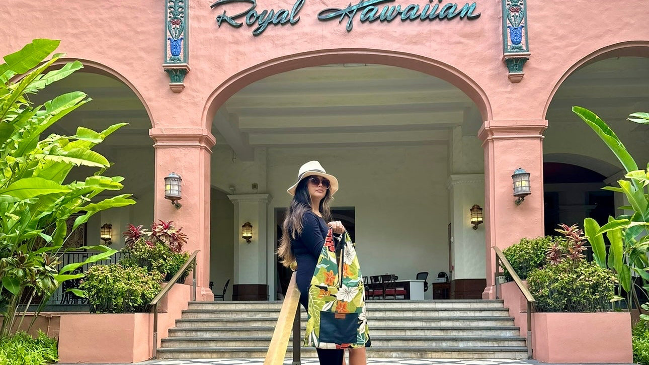 Woman standing on steps in front of a pink building with 'Royal Hawaiian' sign