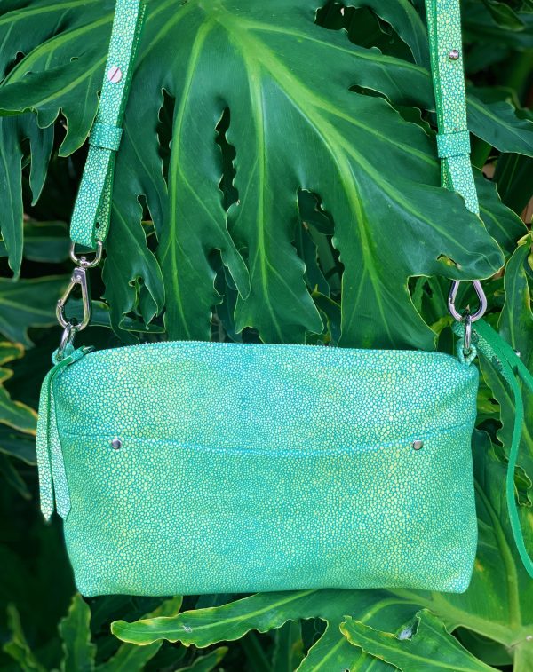 Mermaid green stingray embossed leather bag with a strap and a front pocket on a green leafy background