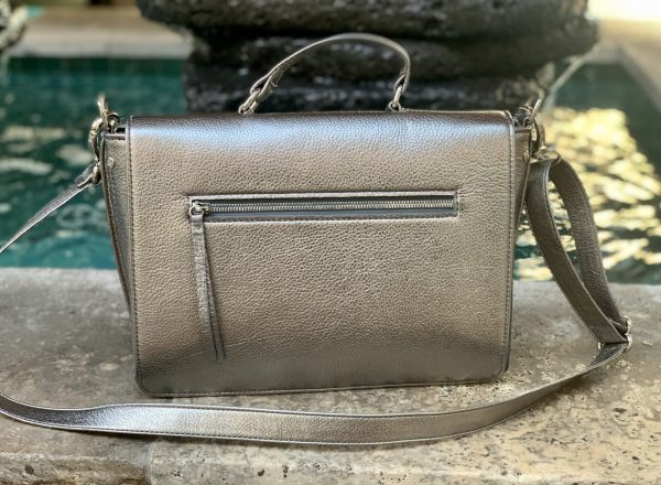 Pewter Metallic leather bag on a stone surface with a blurred fountain in the background.