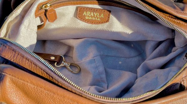 Brandy leather bag opened with Pale shimmer textile lining, zip pocket and key leash.
