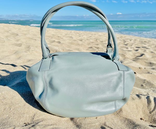 Light grey bag on a sandy beach with ocean in the background
