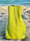 Tahitian lime leather bag side view on a sandy beach with ocean in the background