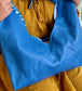 Cobalt Blue leather hobo bag held by a woman wearing a mustard yellow top.
