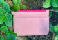  Light Pink pouch back view with a bright pink zipper on a stone surface surrounded by green leaves