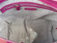 Close-up of theplum purple sheen leather interior with a visible brand logo on a Silver grey metallic textile lining.