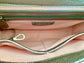 Close-up of the pewter metallic bag  interior with a visible brand logo on a pale pink with iridescent shimmer textile lining, key leash, zip pocket, and two slip mobile pockets.