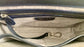 Close-up of the whisky brown leather bag  interior with a visible brand logo on a Silver grey metallic textile lining, key leash, zip pocket, and two slip mobile pockets.