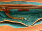 Close-up of the whisky brown leather bag  interior with a visible brand logo on a golden green metallic textile lining, key leash, zip pocket, and two slip mobile pockets.