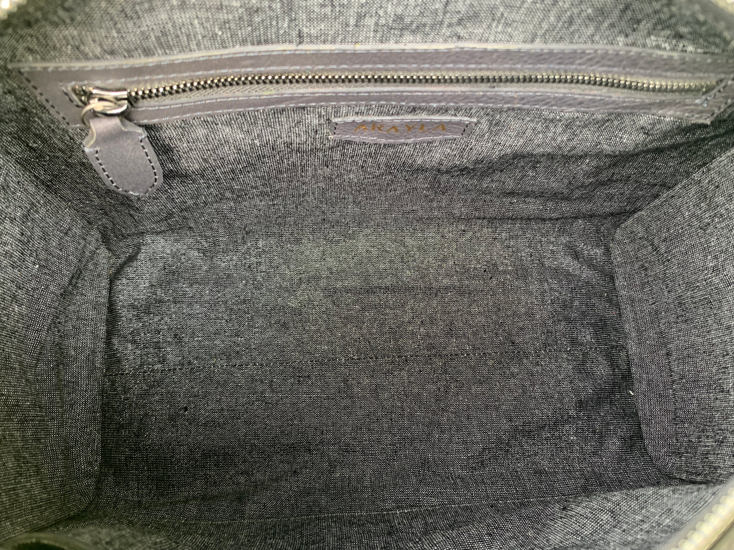 Close-up of the titanium gray leather bag  interior with a visible brand logo on a Silver black textile lining, zip pocket, and two slip mobile pockets.

