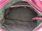 Close-up of the aubergine leather bag  interior with a visible brand logo on a black pearl iridescent textile lining, zip pocket, and two slip mobile pockets.
