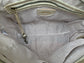 Close-up of the whisky brown leather bag  interior with a visible brand logo on a silver sand textile lining, key leash, zip pocket, and two slip mobile pockets.
