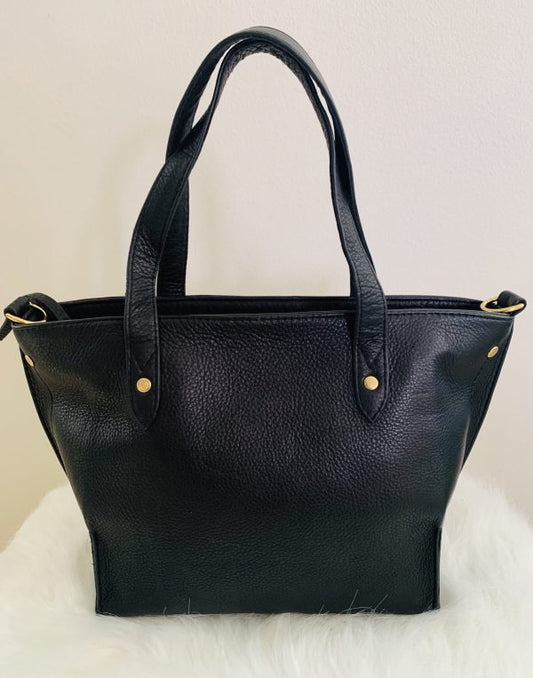Onyx black leather tote bag with gold hardware on a white surface