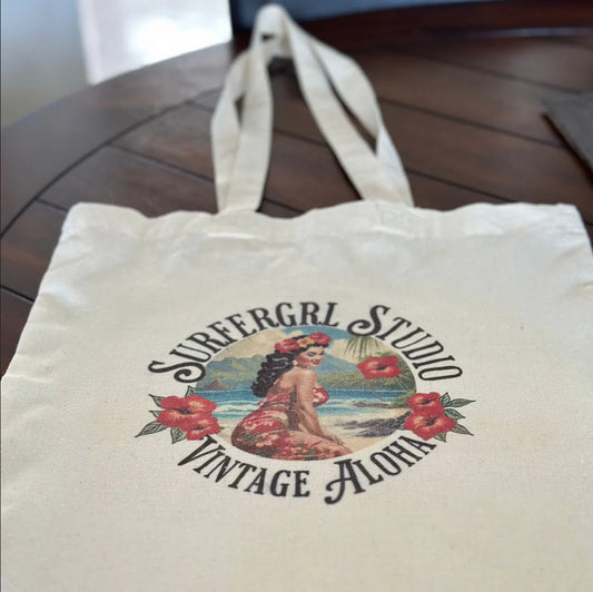 Tote bag with 'Surfergrl Studio Vintage Aloha' design on a wooden surface