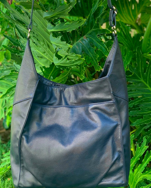 Sapphire leather hobo bag front view against a green leafy background